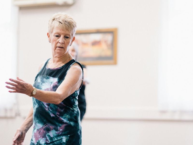 Person in mid-motion during a fluid, dance-like exercise.